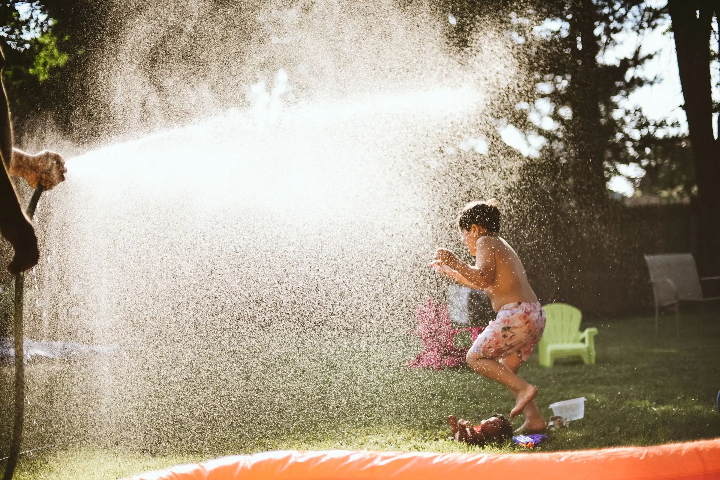 Child playing in a water spray in a backyard on a sunny day