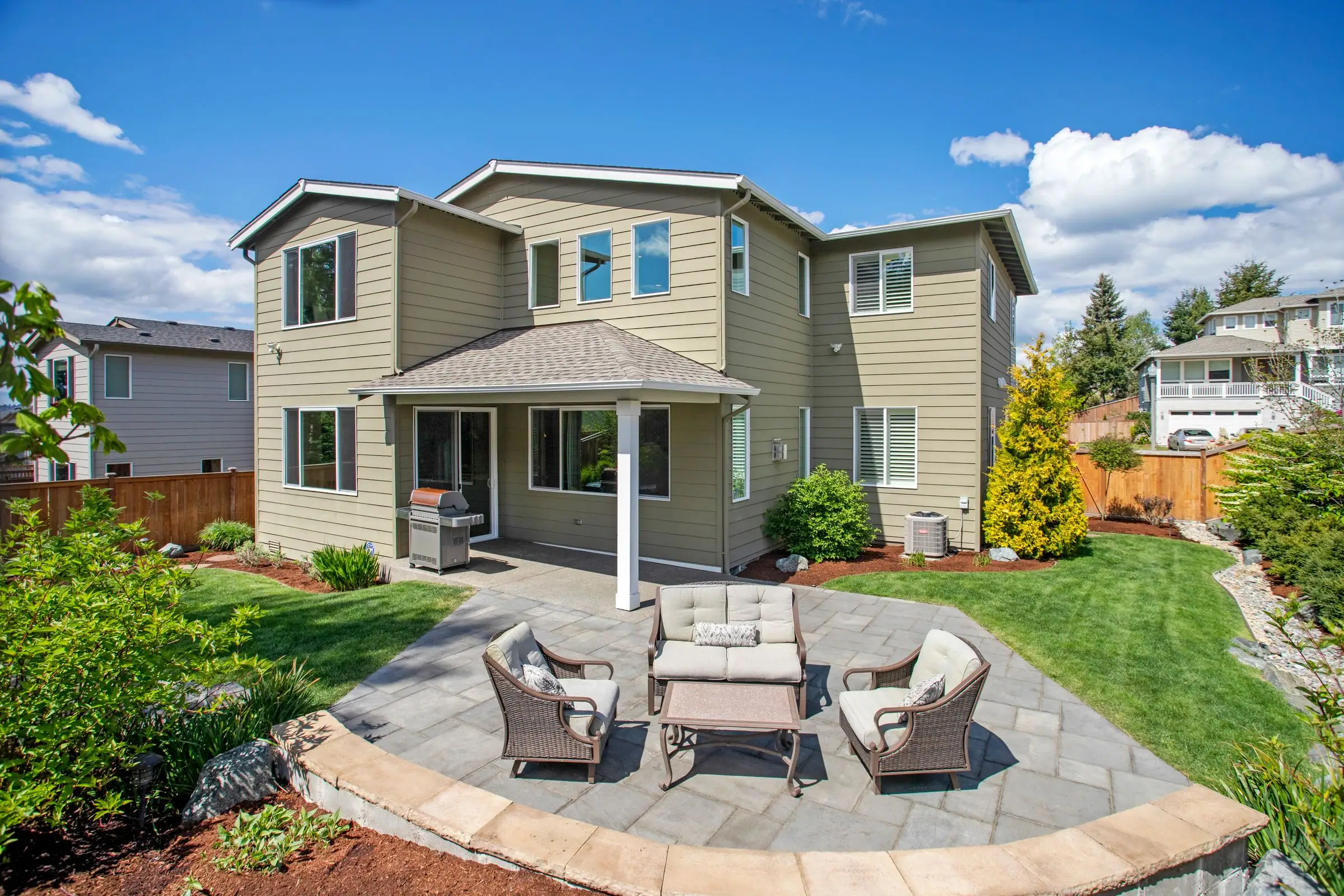 Stone patio with outdoor chairs beside a green lawn