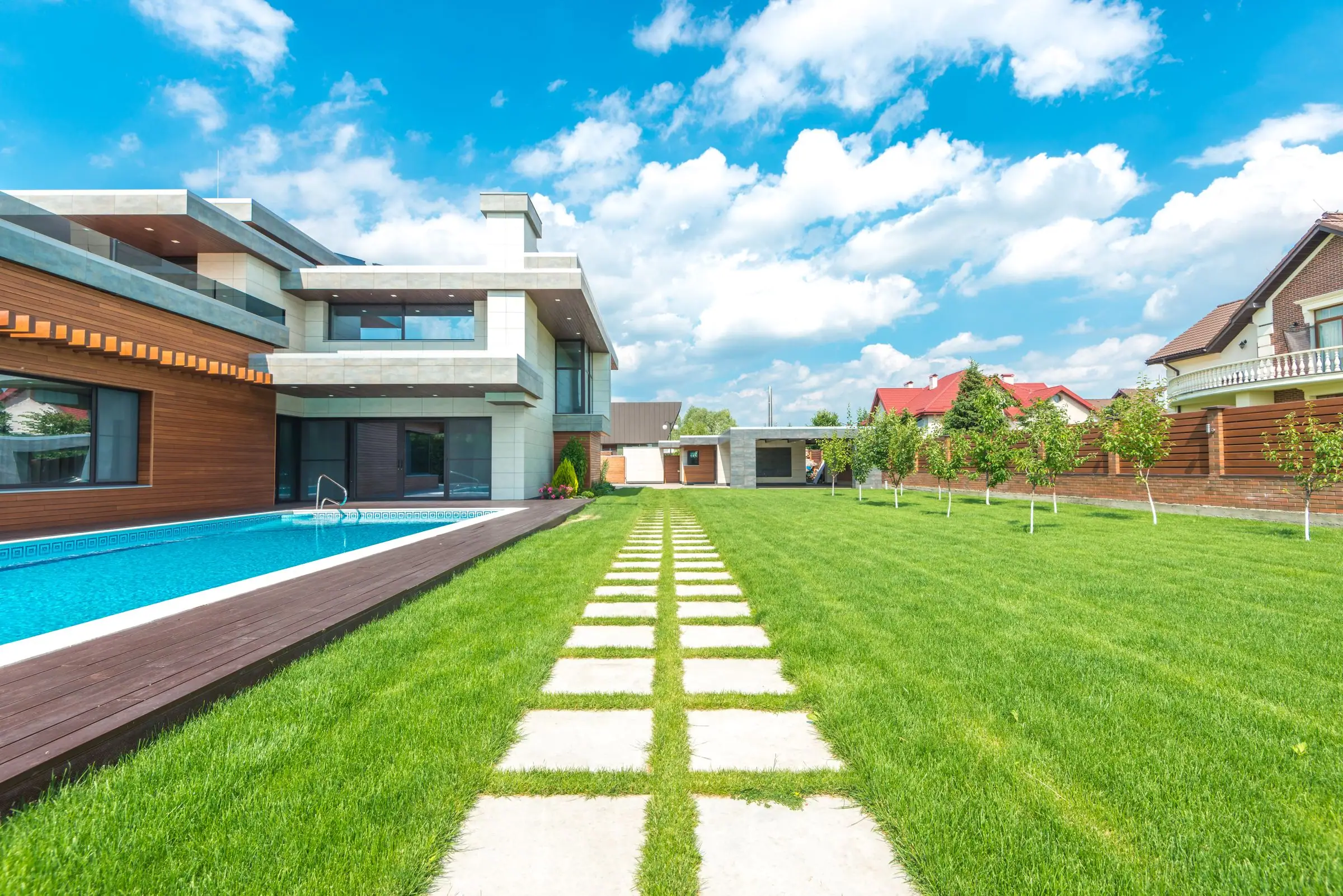 Modern house with a pool, wood deck and a long green lawn