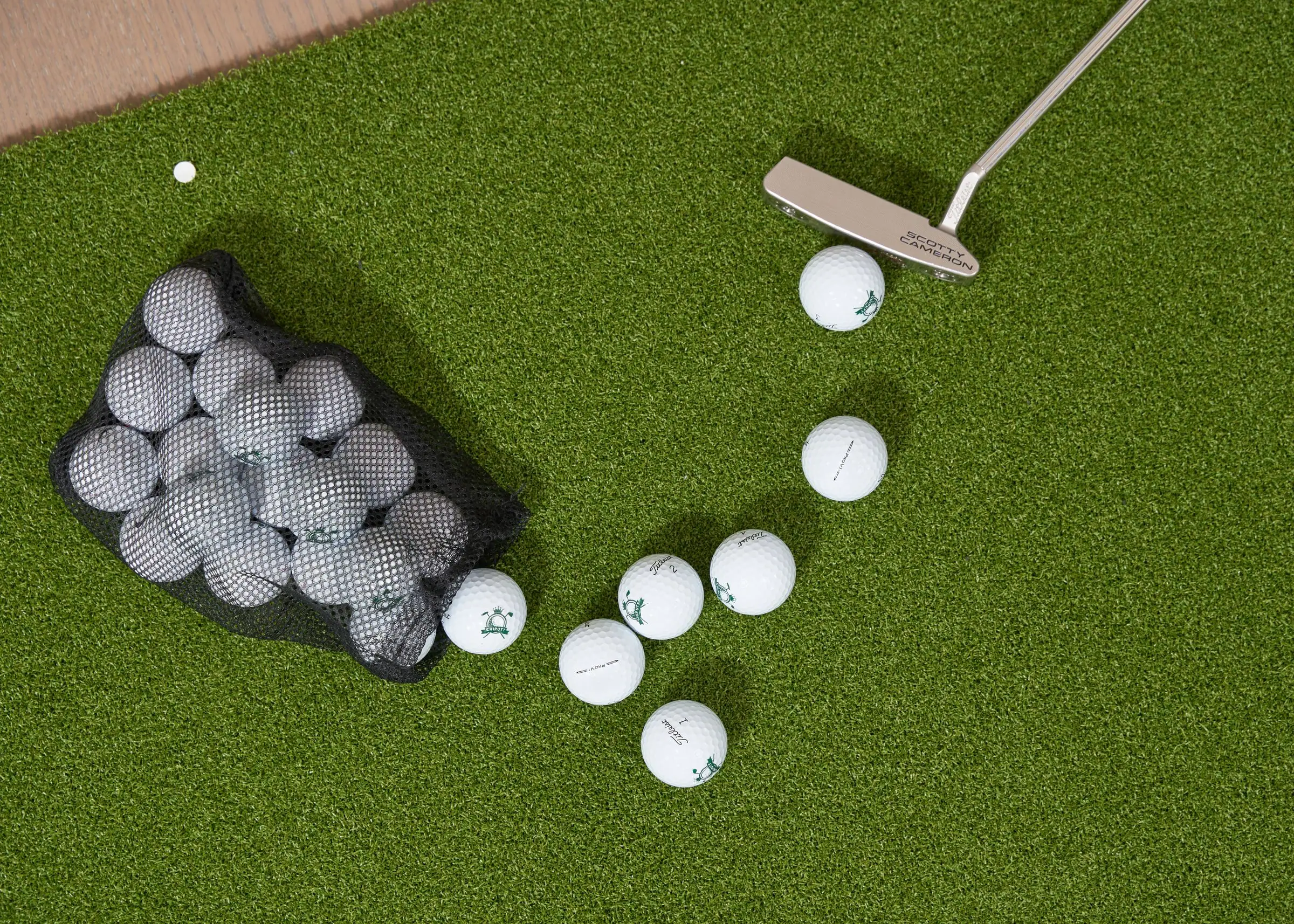 Putter and golf balls on a short putting green surface